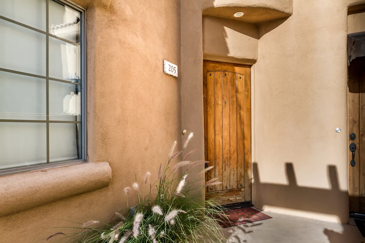 A welcoming exterior entryway showcasing a wooden door, house number, and decorative plants. The scene conveys a sense of arrival and security, emphasizing the townhouse-style private entry mentioned in the section.