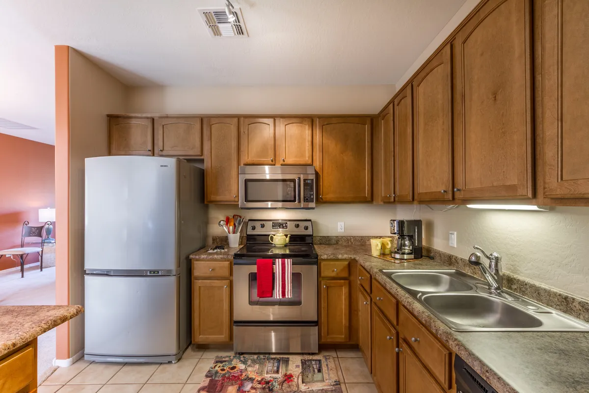 A modern kitchen with stainless steel appliances, granite countertops, and wooden cabinets. The workspace is organized and ready for culinary creativity, hinting at an inviting space for both casual breakfasts and elegant dinners.