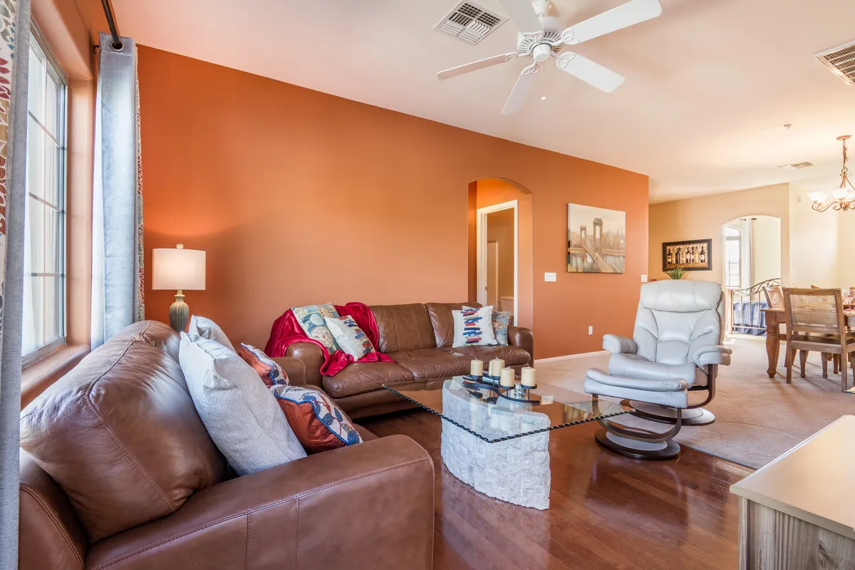 A welcoming living area featuring a plush leather sofa, glass coffee table, and accent pillows. The space is bathed in cozy light from a nearby lamp, creating an inviting atmosphere for relaxing or socializing. The arrangement suggests a communal spot perfect for taking breaks from work, enjoying coffee with friends, or unwinding after a productive day.