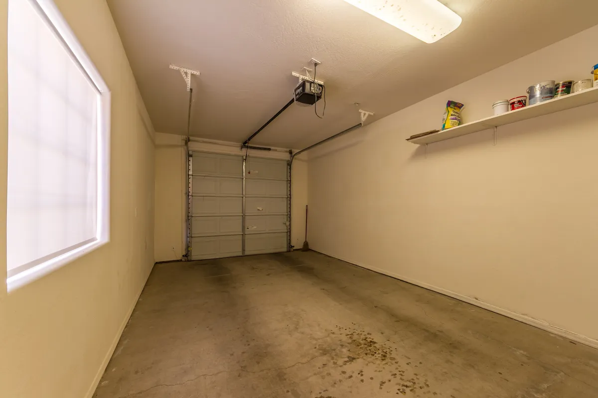 This image displays the interior of a garage, featuring a visible garage door, sturdy shelving, and a concrete floor. The practical layout highlights the space's utility for parking and storage, echoing the 'private garage entrance' mentioned in the section.