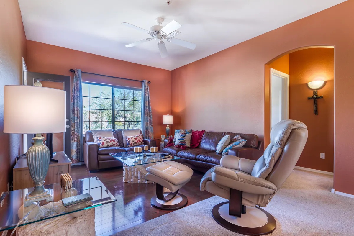 A welcoming living area featuring a brown leather sofa topped with decorative pillows, a glass coffee table, and ample natural light from a large window. The space is designed for relaxation, reading, or unwinding on the couch—ideal for flexible sleeping with a pull-out sofa.